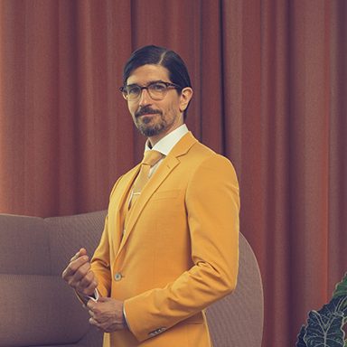 Man with a Yellow suit and glasses looking serious